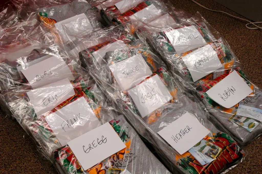Group t-shirts sorted into labeled bags, one bag per person, ready to hand out
